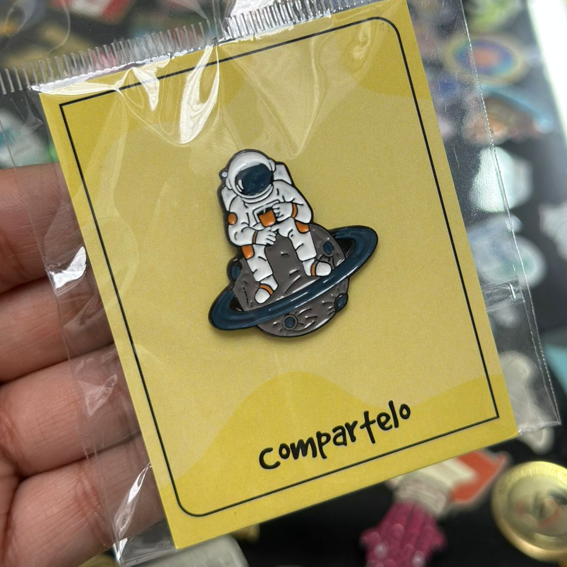 Pin astronauta sentado en saturno